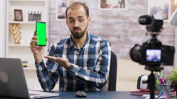 jovem e famoso influenciador filmando uma Reveja do uma telefone com verde tela. criativo conteúdo O Criador. video