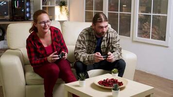 Couple in their 30's relaxing playing video games using wireless controllers. Happy relationship.