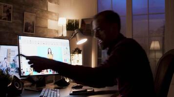 Young photographer listening music on headphones while retouching photos during night time. video