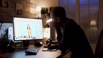 Tired photographer working on photos during night time using retouching software. video