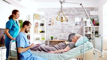 Team of male and female nurses checking an old lady lying in hospital bed in a retirement home video