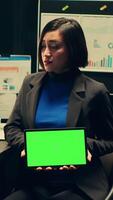 Vertical Video Private detective using tablet showing greenscreen template in incident room, working with witness statements and classified records. Agent holding device with isolated mockup. Camera A.