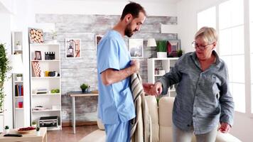 Male nurse helping senior woman getting dressed in nursing home video