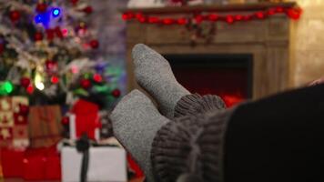 Close up of woman feet moving and relaxing on christmas day on boyfriend legs. Christmas couple magic cozy warm fireplace, spending festive holidays together in family video