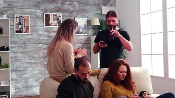 Boring friends using their phone while sitting on the couch in living room. Man taking a sip of beer. video