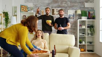 giovane donna in arrivo con Pizza per orologio un' calcio incontro su tv con sua gli amici. contento amici video