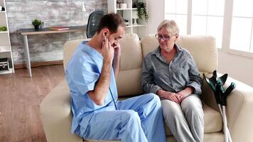 Male nurse listening old woman heart beat with a stethoscope in retirement home video