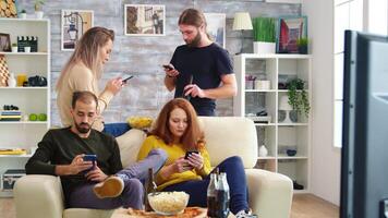 Young man taking a sip of beer while using his smartphone. Friends browsing on mobile phone. video