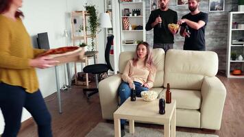 Girl pranking her friends with pizza in living room. Cheerful friends relaxing together. video