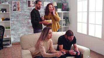 Happy bearded man with long hair for his victory against his girlfriend while playing video games using wireless controller.