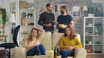 grupp av vänner tittar på en fotboll match i levande rum dricka öl och äter snacks. video