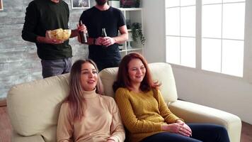 Zoom in shoot of young woman eating popcorn and drinking soda while watching tv with her friends. video