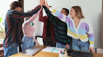 een groep van multiraciaal mensen in een kantoor geven elk andere hoog vijven video