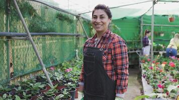 une hispanique femme dans un tablier sourit tandis que permanent dans une jardin video