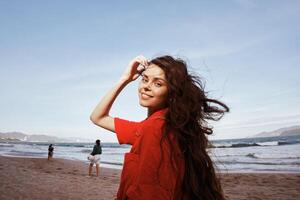 sonriente mujer en rojo ropa, disfrutando divertido y libertad en el playa foto