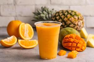 orange mango pineapple cocktail juice with raw fruits served in glass isolated on table top view of healthy morning drink photo