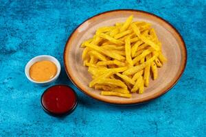 Crispy French Fries or potato chips with mayo dip and tomato sauce served in a plate side view view photo