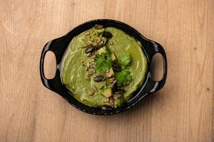 Green Hummus served in dish isolated on table top view of arabian food photo