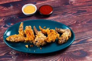 Crispy chicken wings with tomato sauce and mayo dip isolated on cutting board side view of fastfood photo