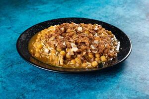 Spicy Chana chat masala chotpoti in a black dish isolated on background top view of indian, bangali and pakistani food chat pata food photo