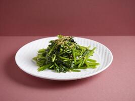 Stir-Fried Spinach with Garlic with chopsticks served in a dish isolated on mat side view on grey background photo