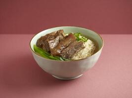 Stewed Beef Brisket Noodle with chopsticks served in a bowl isolated on mat side view on grey background photo