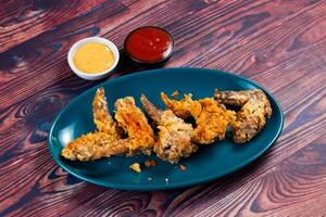 Crispy chicken wings with tomato sauce and mayo dip isolated on cutting board side view of fastfood photo