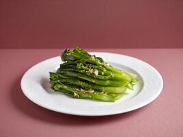 Stir-fried Hong Kong Kai Lan with Garlic with chopsticks served in a dish isolated on mat side view on grey background photo