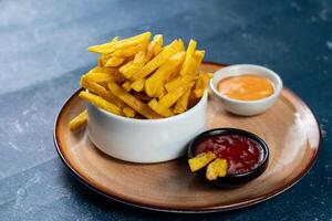 Crispy French Fries or potato chips with mayo dip and tomato sauce served in a plate side view view photo