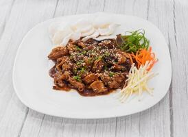 Beef Bulgogi served in dish isolated on grey wooden background side view of fastfood photo