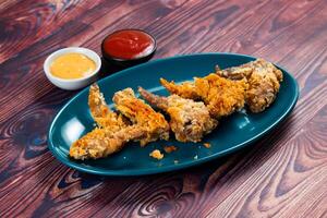Crispy chicken wings with tomato sauce and mayo dip isolated on cutting board side view of fastfood photo