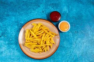 Crispy French Fries or potato chips with mayo dip and tomato sauce served in a plate side view view photo