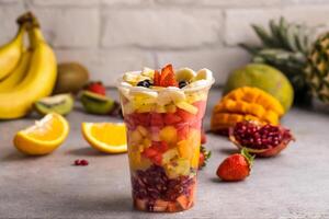 Fruit salad with mango, banana, strawberry, pineapple, orange, lime, kiwi and blackberry served in glass isolated on table top view of healthy food photo