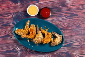 Crispy chicken wings with tomato sauce and mayo dip isolated on cutting board side view of fastfood photo