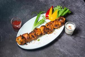 Spicy Chicken Tikka boti kabab with chutney, raita, salad served in dish isolated on grey background top view of indian and bangladesh food photo