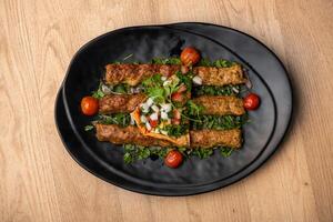 Turkish Halabi kebabwith cherry tomato served in dish isolated on table top view of arabian food photo