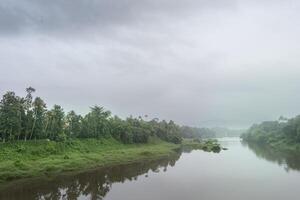 A landscape view of a calm river with green trees and mountain in India photo