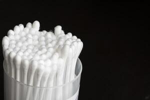 Macro view of white cotton ear cleaning buds arranged in black background nicely in a container photo