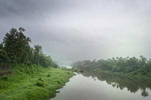 A landscape view of a calm river with green trees and mountain in India photo