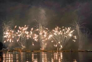 un vistoso fuego trabajos durante un celebracion en el río con hermosa reflexión en el agua foto