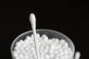 Macro view of white cotton ear cleaning buds arranged in black background nicely in a container photo