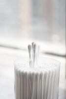 Macro view of white cotton ear cleaning buds arranged in white backgroud nicely in a container photo