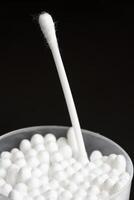 Macro view of white cotton ear cleaning buds arranged in black background nicely in a container photo