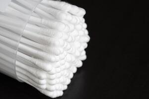 macro ver de blanco algodón oído limpieza brotes arreglado en negro fondo bien en un envase foto