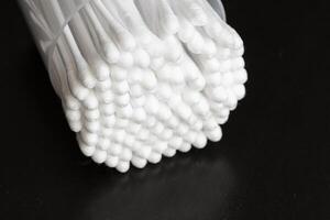 Macro view of white cotton ear cleaning buds arranged in black backgroud nicely in a container photo