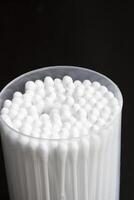 Macro view of white cotton ear cleaning buds arranged in black backgroud nicely in a container photo