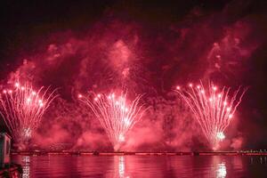 un vistoso fuego trabajos durante un celebracion en el río con hermosa reflexión en el agua foto