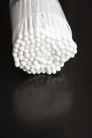 Macro view of white cotton ear cleaning buds arranged in black backgroud nicely in a container photo