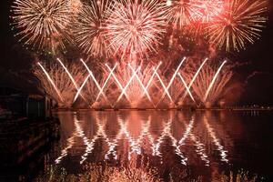 un vistoso fuego trabajos durante un celebracion en el río con hermosa reflexión en el agua foto