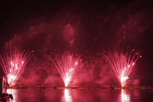 un vistoso fuego trabajos durante un celebracion en el río con hermosa reflexión en el agua foto